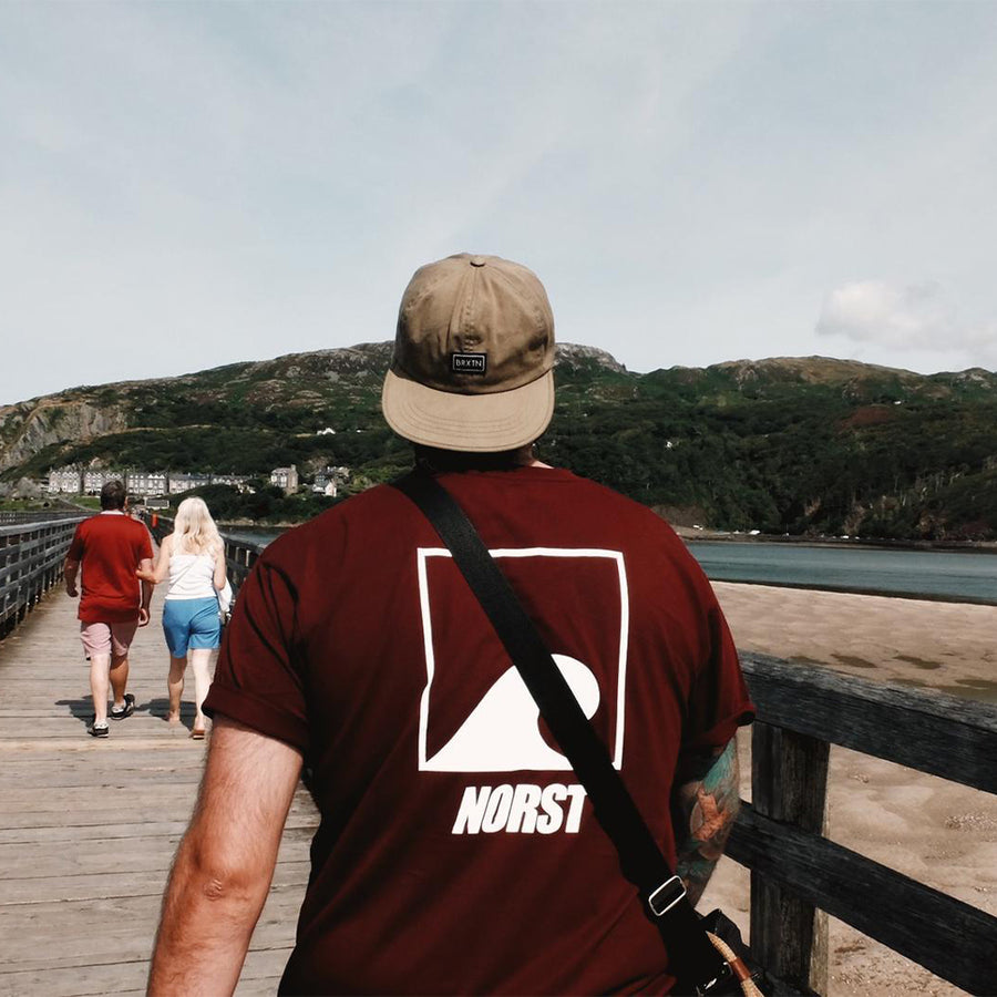 A person in a Norst t-shirt looking over a harbour