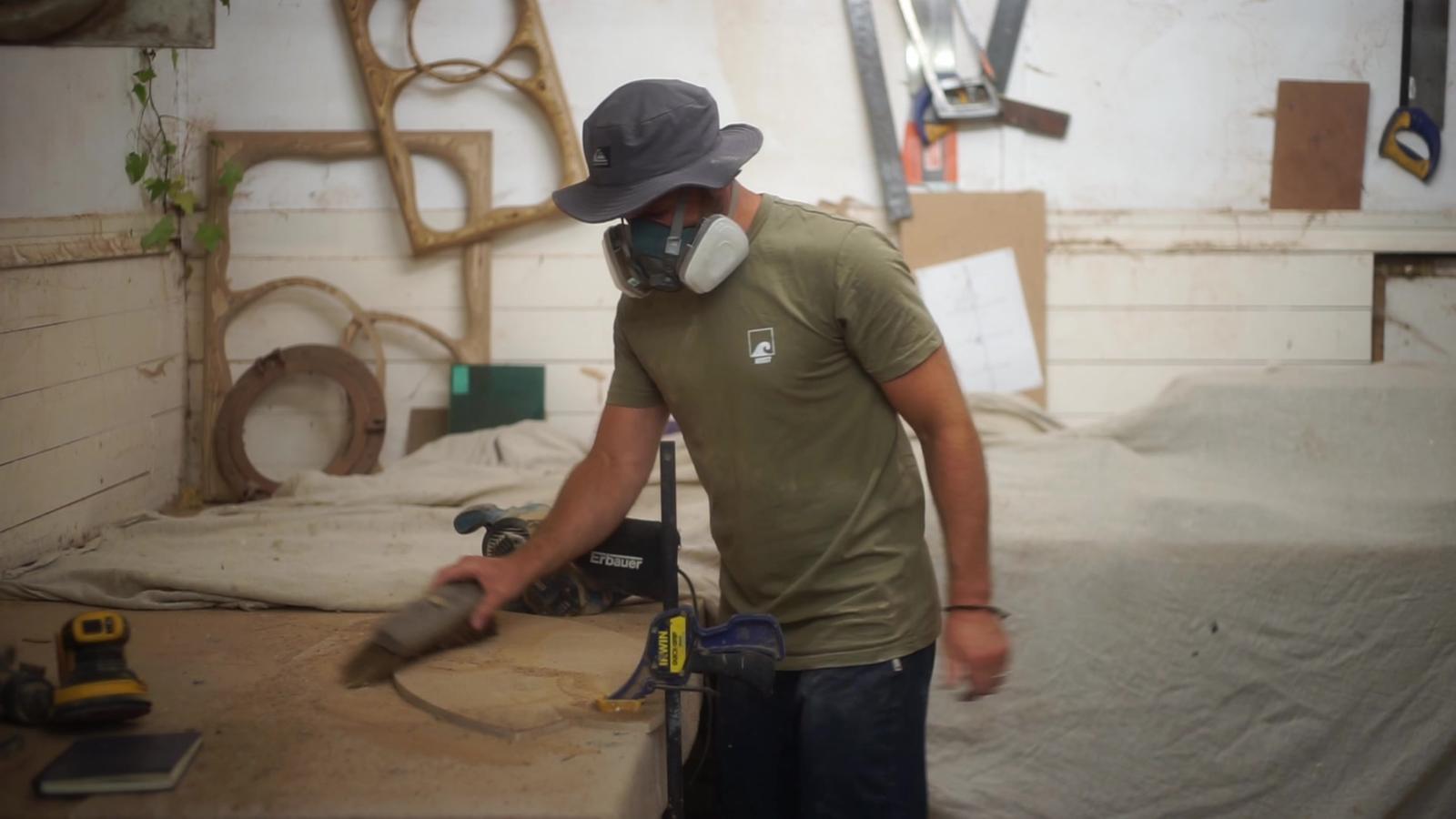 Dan sanding a board in a respirator.