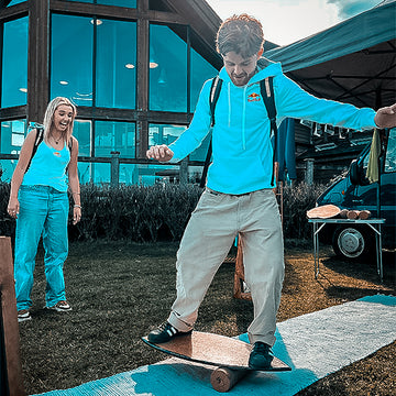 A rider in a blue hoodie balancing on a Norst board and roller at an outdoor event