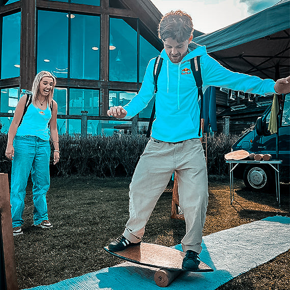 A rider in a blue hoodie balancing on a Norst board and roller at an outdoor event