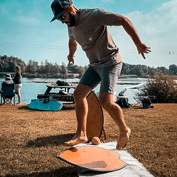 A rider balancing on a Norst Surf Balance Board and roller beside a lake
