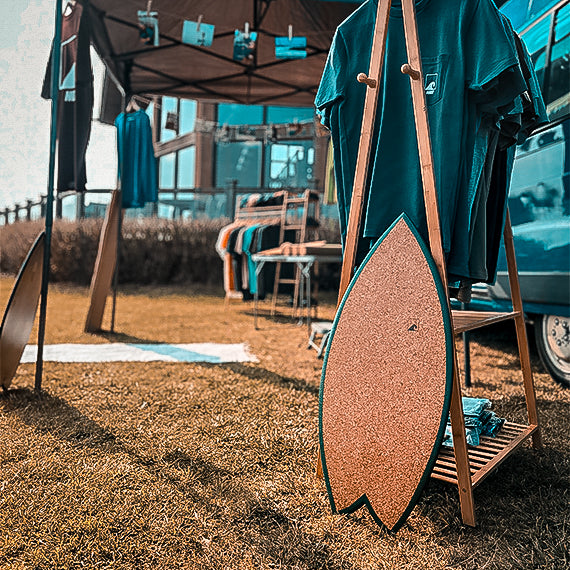 A Norst Surf Balance Board leaning against a clothing rail at an outdoor event