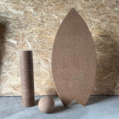 A Norst Surf Balance Board standing upright with a cork roller and cork ball
