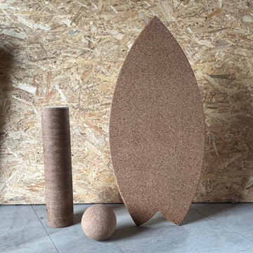 A Norst Surf Balance Board standing upright with a cork roller and cork ball