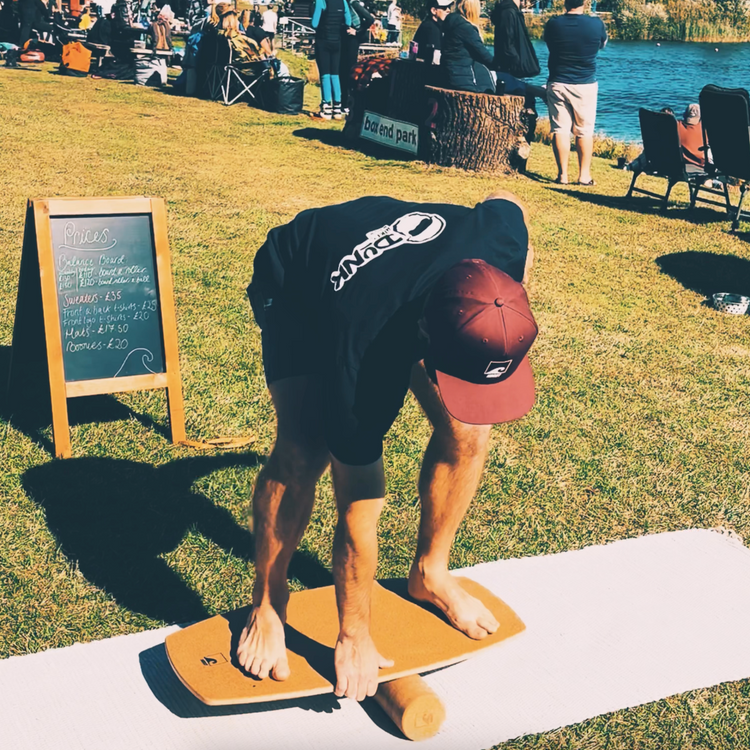 A rider crouching to set a Norst Freestyle Balance Board on its roller at an outdoor event