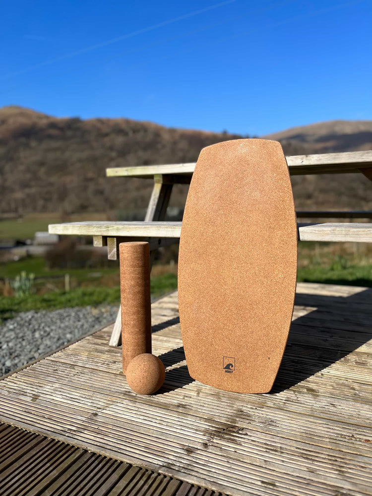 A Norst Freestyle Balance Board with a cork roller and cork ball on decking, hills behind