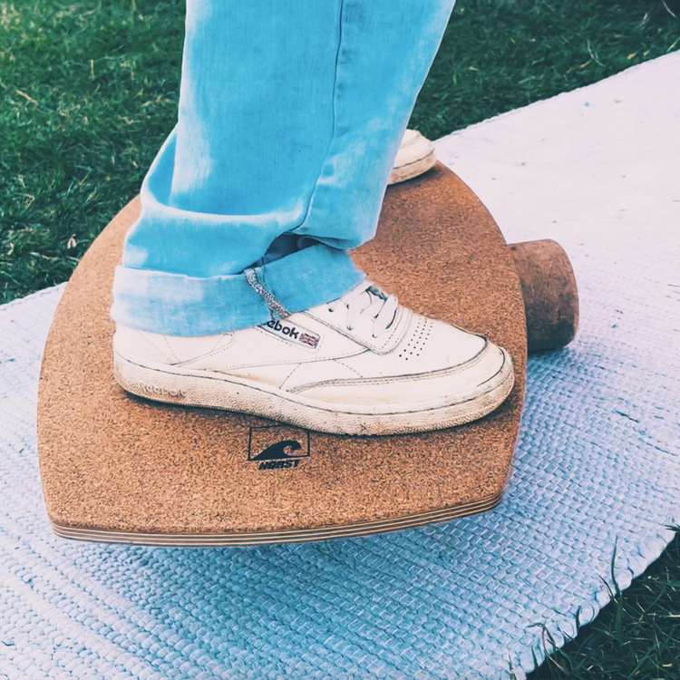 Close-up of a foot on the cork deck of a Norst Freestyle Balance Board, roller beneath