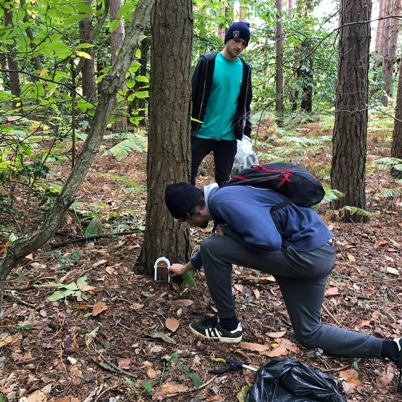 Two people in a wood, one crouching.
